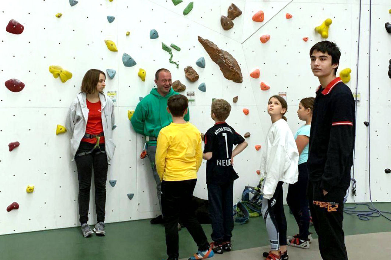 Kinder stehen vor einer Kletterwand