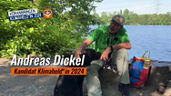 Unser Gewinner des Nachhaltigkeitspreises Klimaheld:in 2024 Andreas Dickel sitzt zusammen mit seinem schwarzen Hund Bella am Ewaldsee in Herten und streichelt dem Hund über den Kopf. Neben sich steht die Tüte und liegt die Zange, mit der er den Müll einsammelt. Es ist ein schöner sonniger Tag 