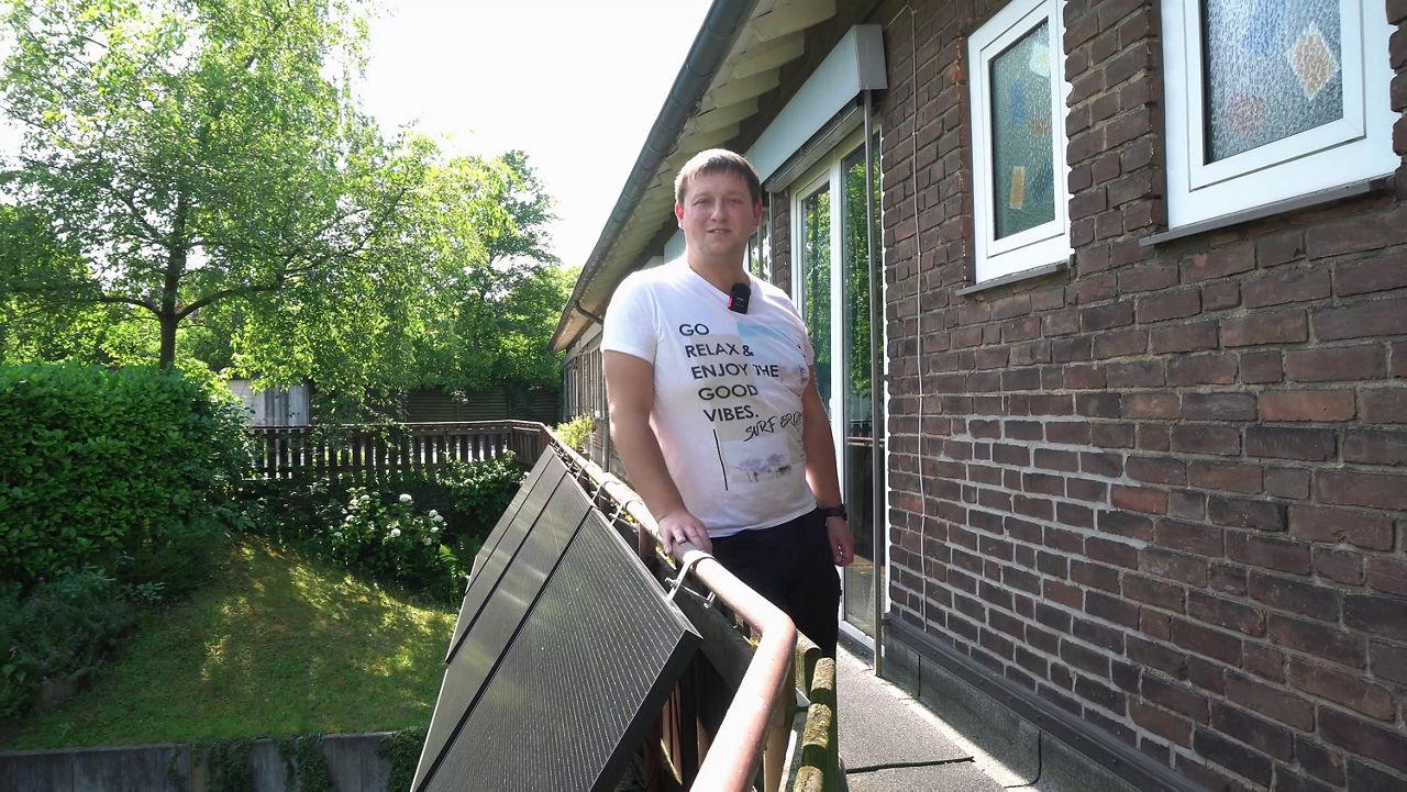 Andreas Vobker vom Verein Green Anton steht dem Balkon eines Kindergartens an die Brüstung angelehnt und lächelt in die Kamera. An der Brüstung sieht man mehrere Solarpanele angebracht, sogenannte Balkonkraftwerke. Green Anton belegt beim Klimahelden 2024 den 1. Platz bei den Vereinen.