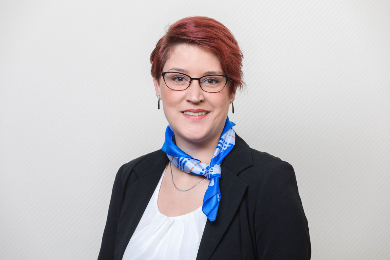 Eine lächelnder Frau schaut in die Kamera.