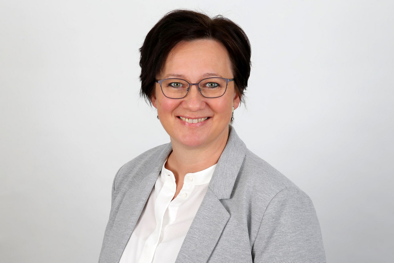 Eine lächelnder Frau schaut in die Kamera.