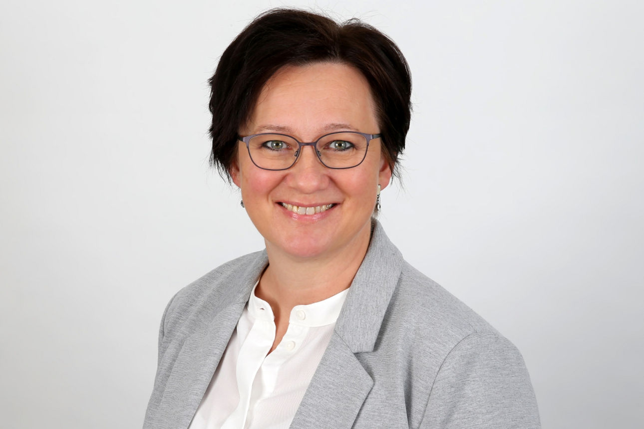 Eine lächelnde Frau schaut in die Kamera.