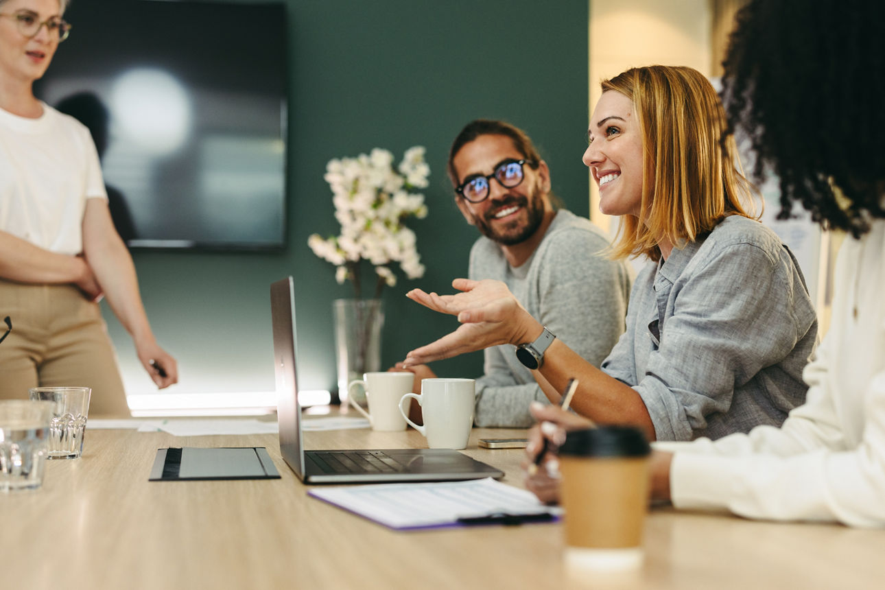 Cheerful businesswoman having a discussion with her colleagues in a boardroom. Group of happy businesspeople sharing ideas during a meeting in a modern workplace.; Shutterstock ID 2140178957; purchase_order: Website | Stellenangebote; job: ; client: ; other: 