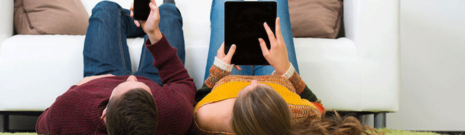 Ein Mann und eine Frau liegen auf dem Boden und schauen auf ihre Handys
