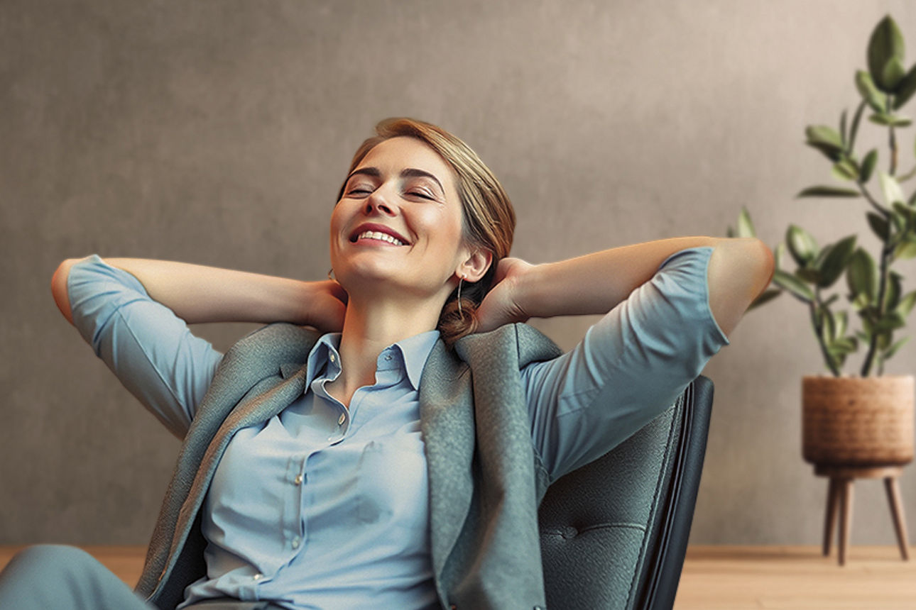 Eine lächelnde Frau sitzt in einem Sessel und verschränkt die Arme hinter dem Kopf