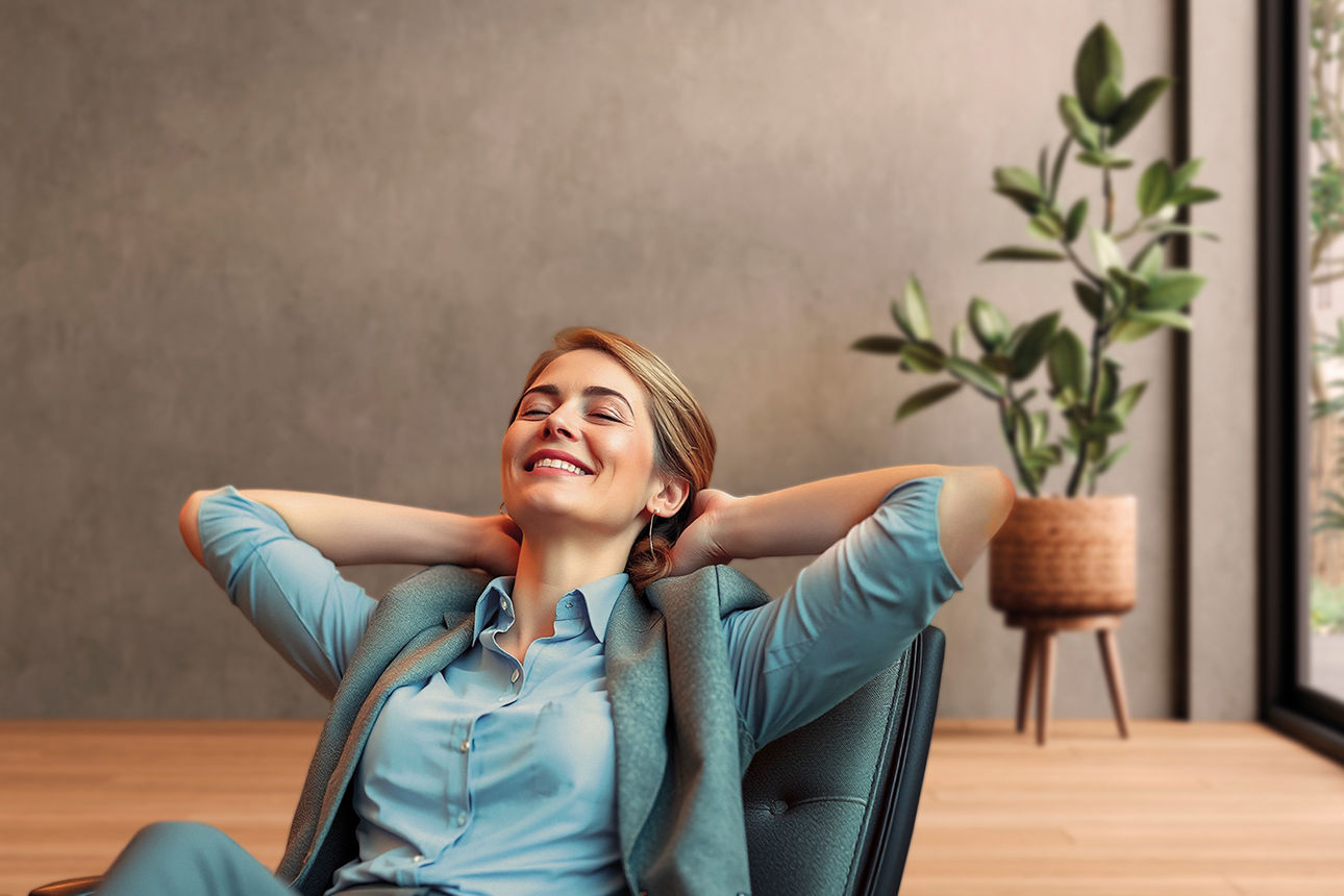 Eine lächelnde Frau sitzt in einem Sessel und verschränkt die Arme hinter dem Kopf