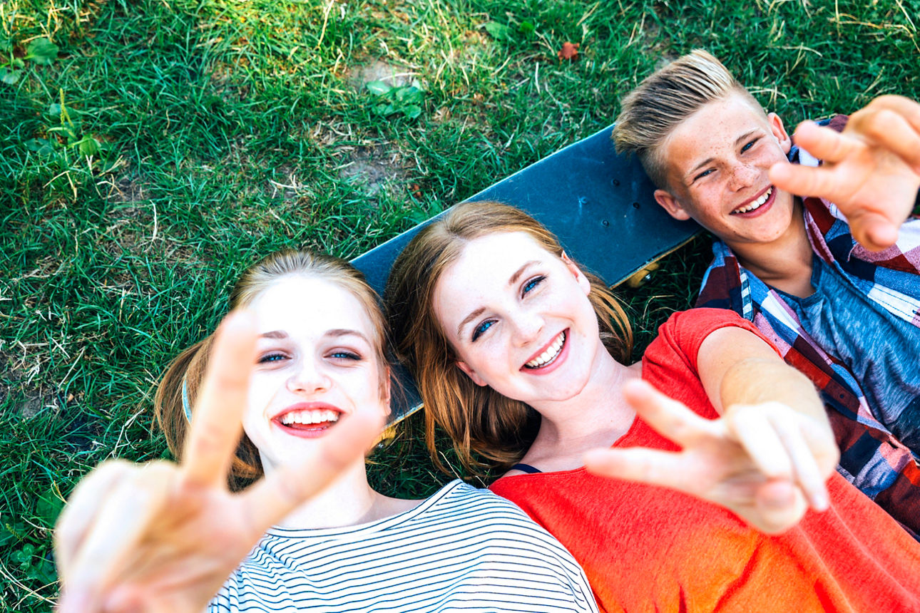 Jugendliche lachend auf Gras liegend