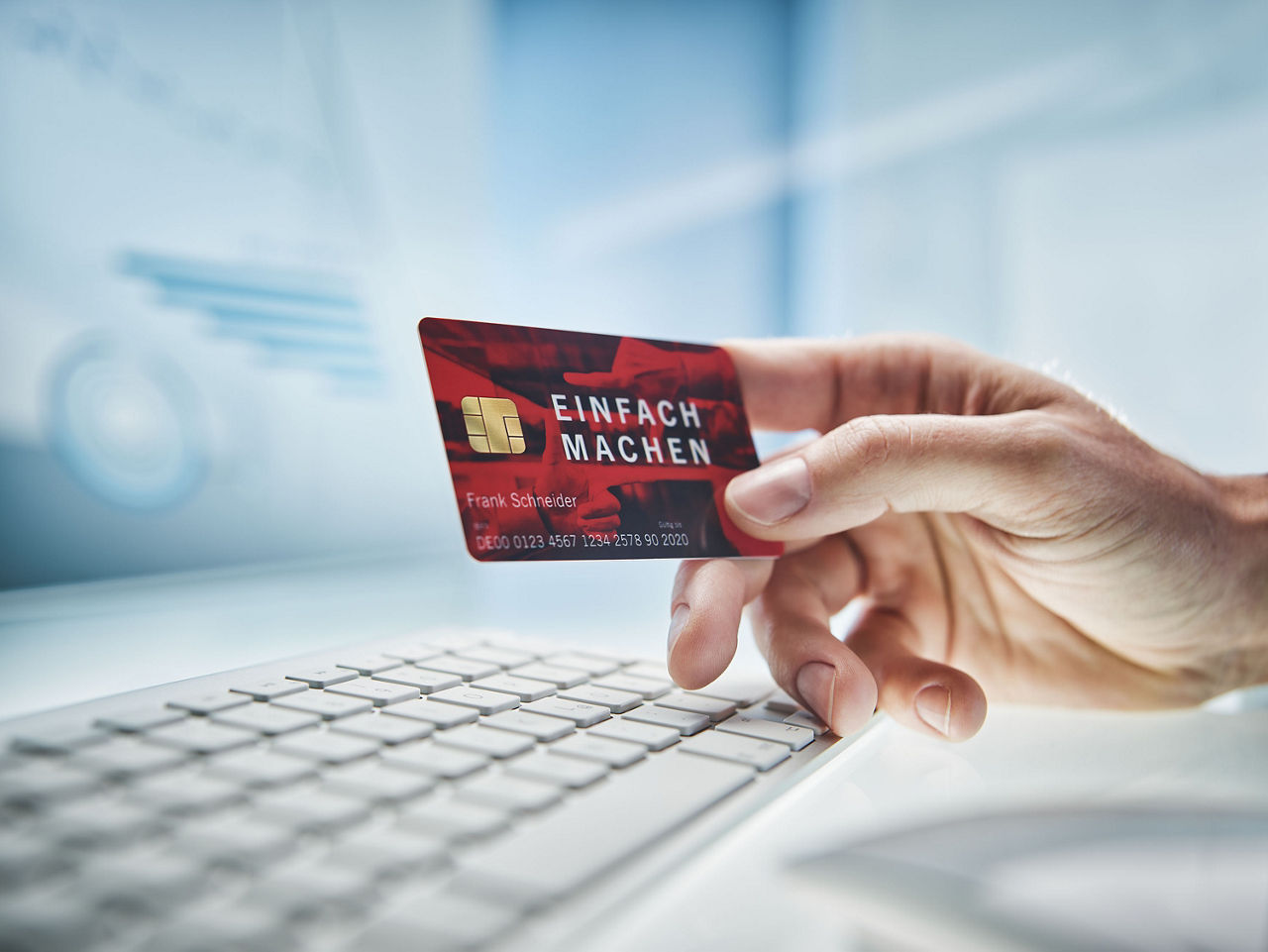 Männliche Hand hält eine rote Bankkarte