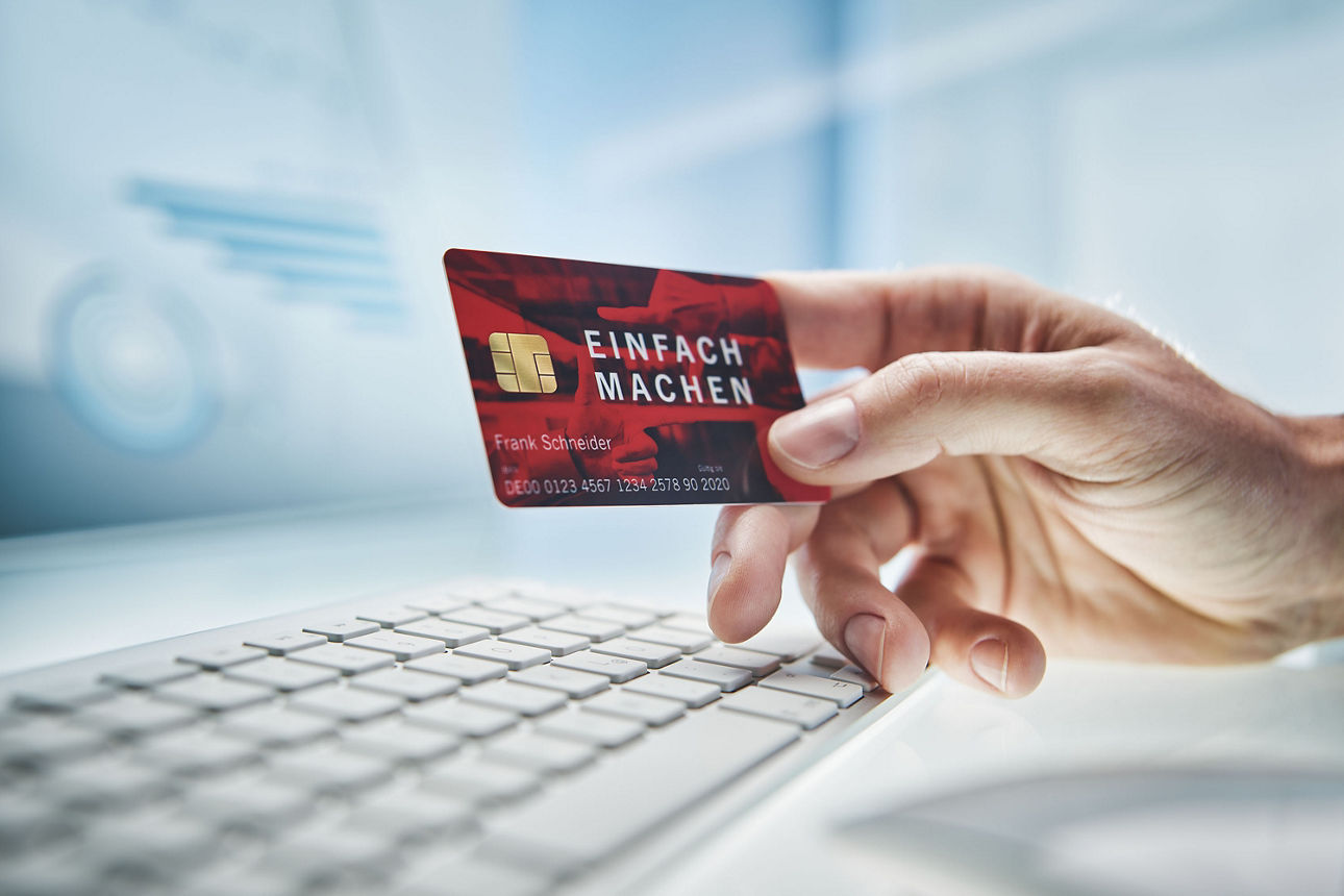 Männliche Hand hält eine rote Bankkarte.