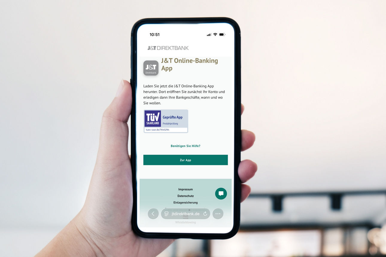 Eine Hand hält ein Smartphone und zeigt die App der J&amp;T Banka, a.s., Zweigniederlassung Deutschland