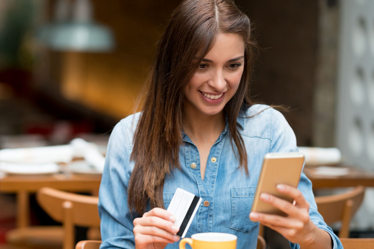Junge Frau mit Karte und Handy in der Hand im Cafe