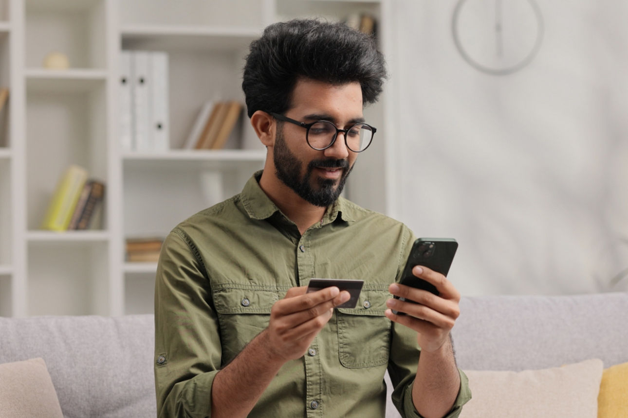 Mann mit Handy und Karte in der Hand sitzt auf einer Couch