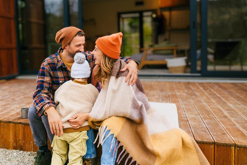 Mann und Frau sitzen auf einer Terrassenstufen und davor steht ein Kind
