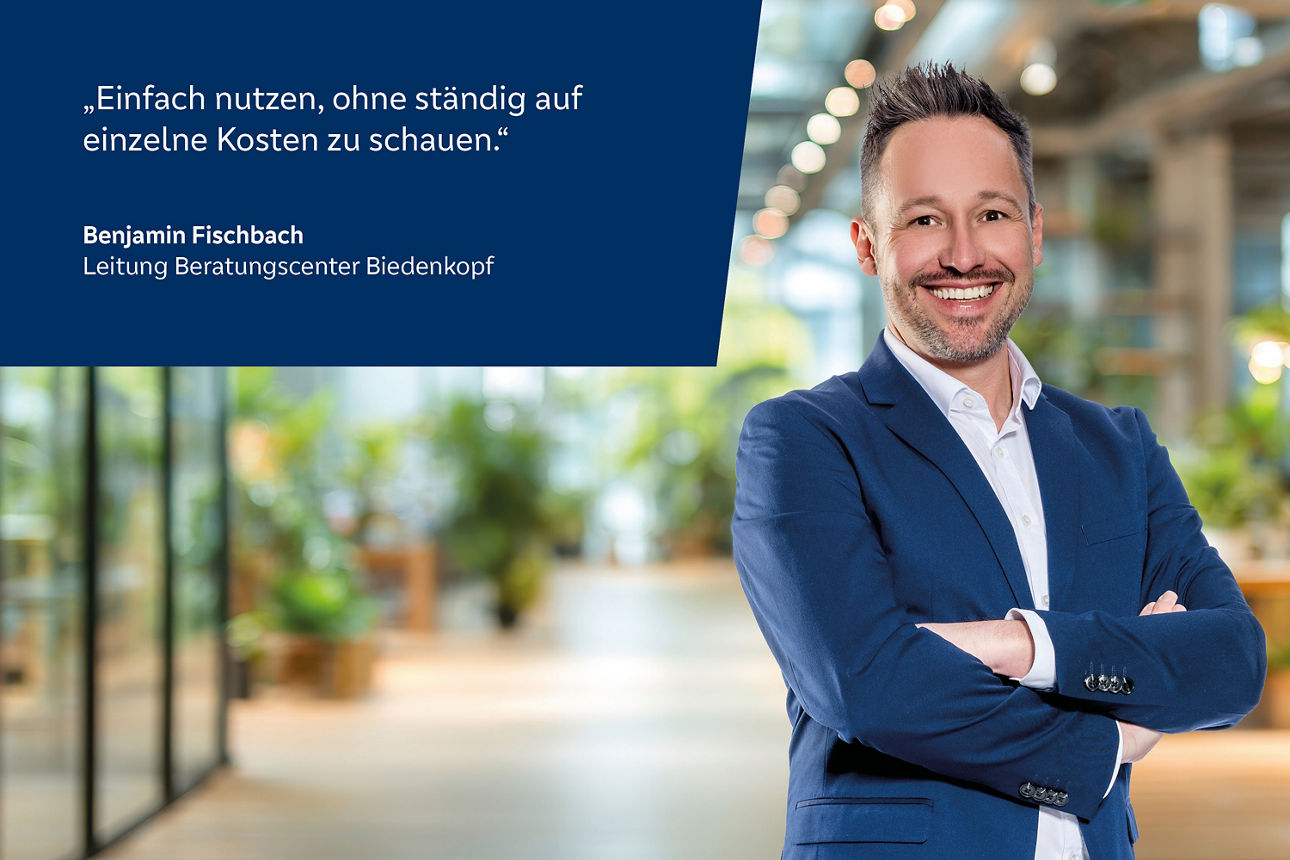 Mann mit verschränkten Armen in blauem Sakko vor unscharfem Büroflur mit Zitat von Benjamin Fischbach