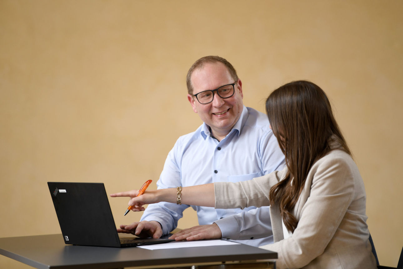 Ein Mann und eine Frau sitzen am Tisch vor einem Notebook
