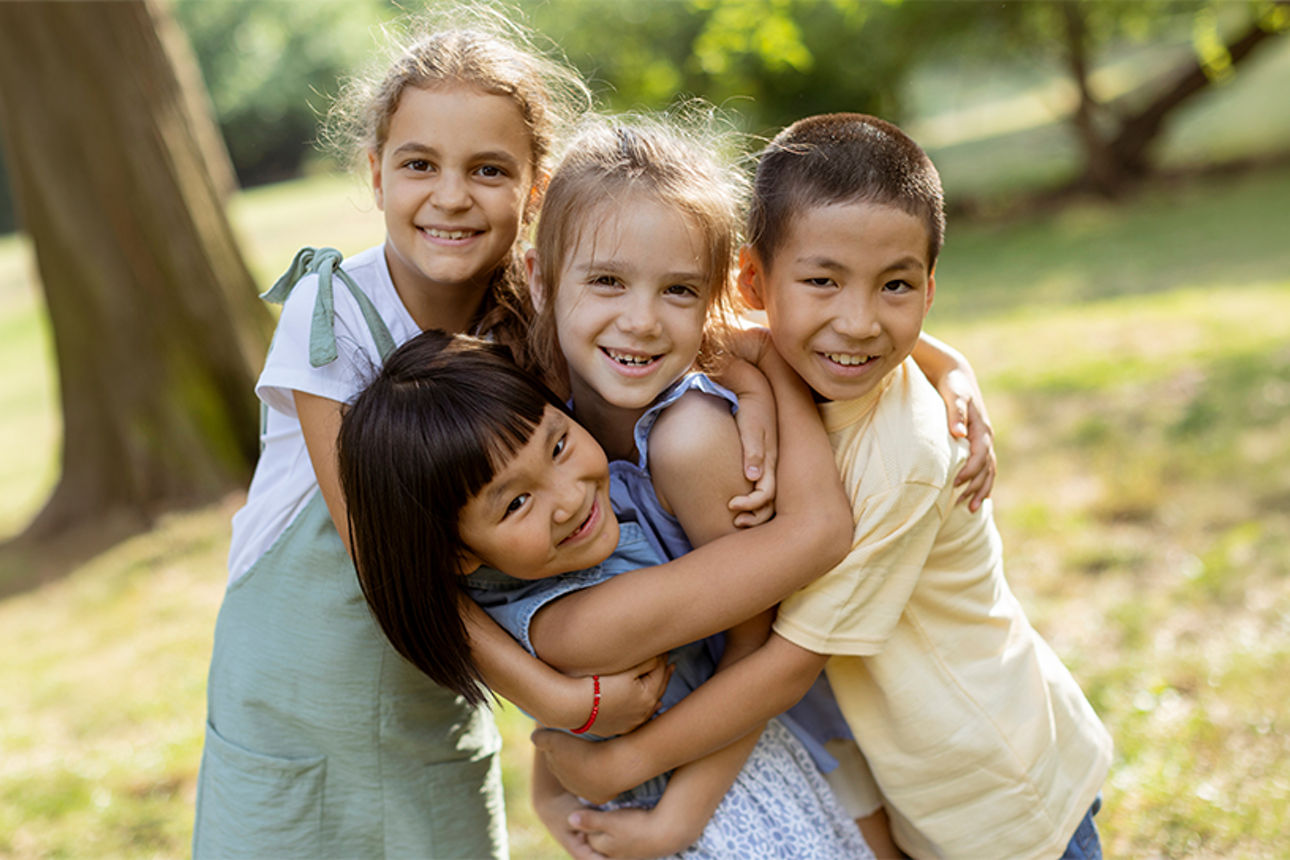 Kinder die sich lachend in den Armen liegen in der Natur