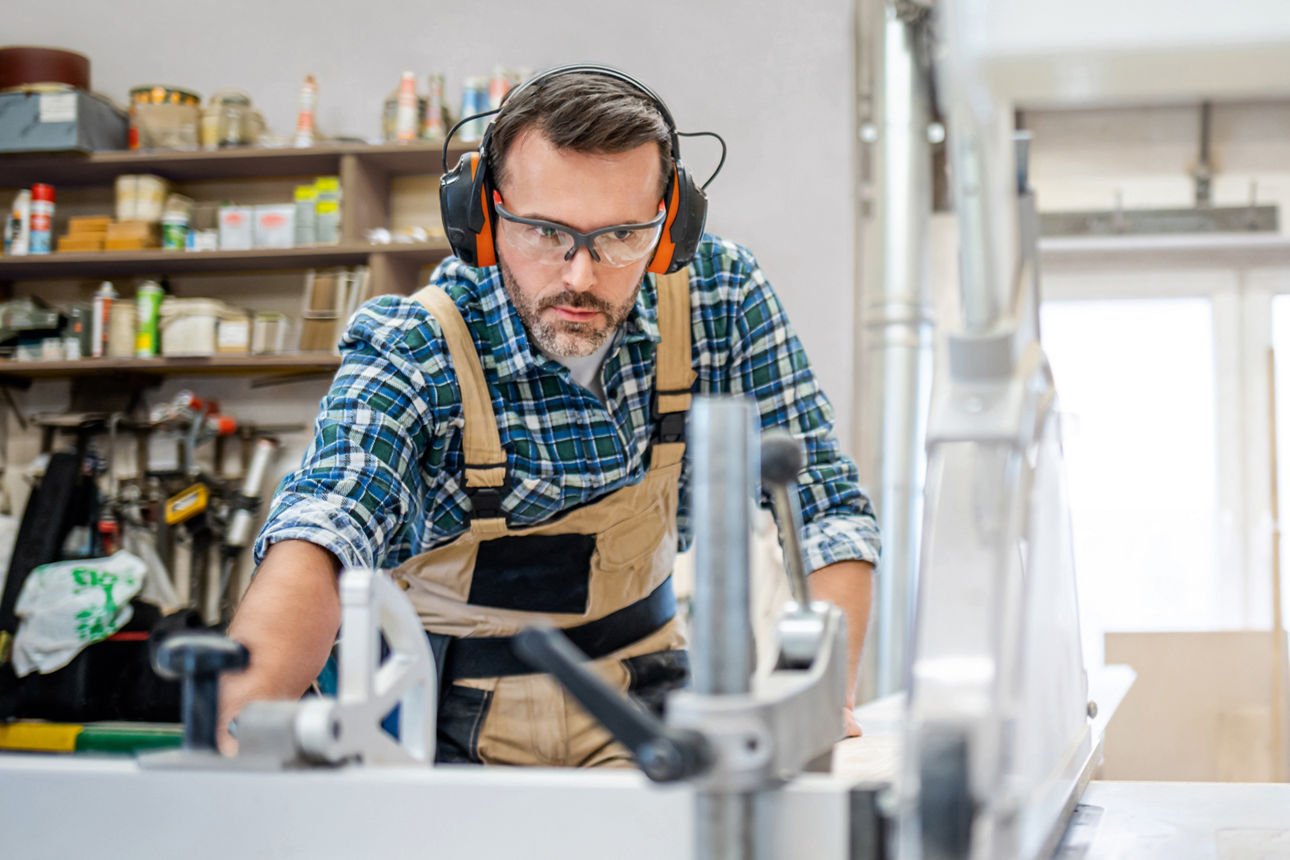 Ein Mann steht an der Säge und sägt Holz in der Werkstatt