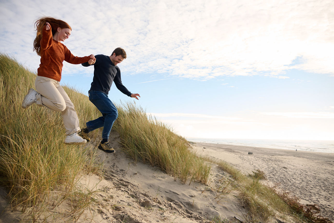 Paar läuft am Strand die Düne nach unten