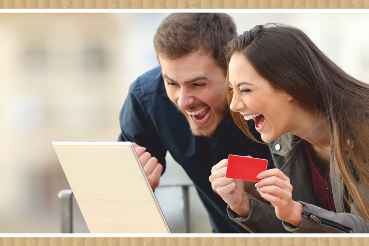 Junges Paar schaut lachend in einen Laptop