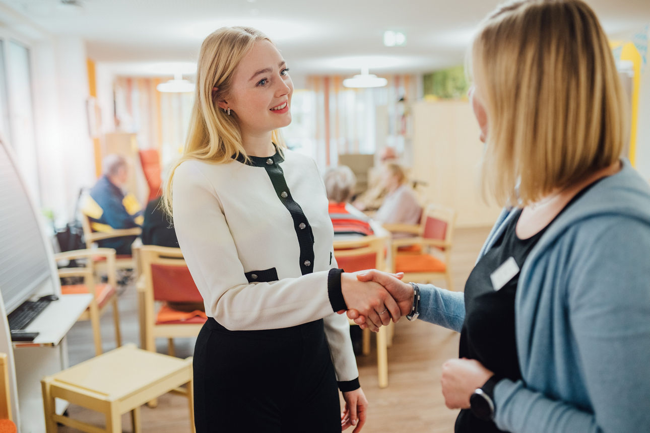 Eine Mitarbeiterin und eine Kundin reichen sich die Hand