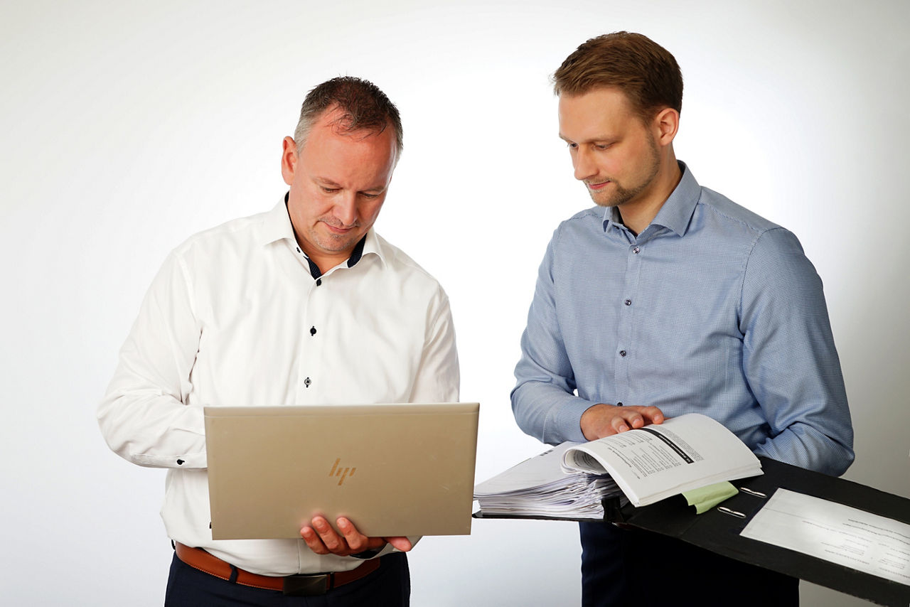 Zwei Mitarbeiter schauen gemeinsam in Unterlagen