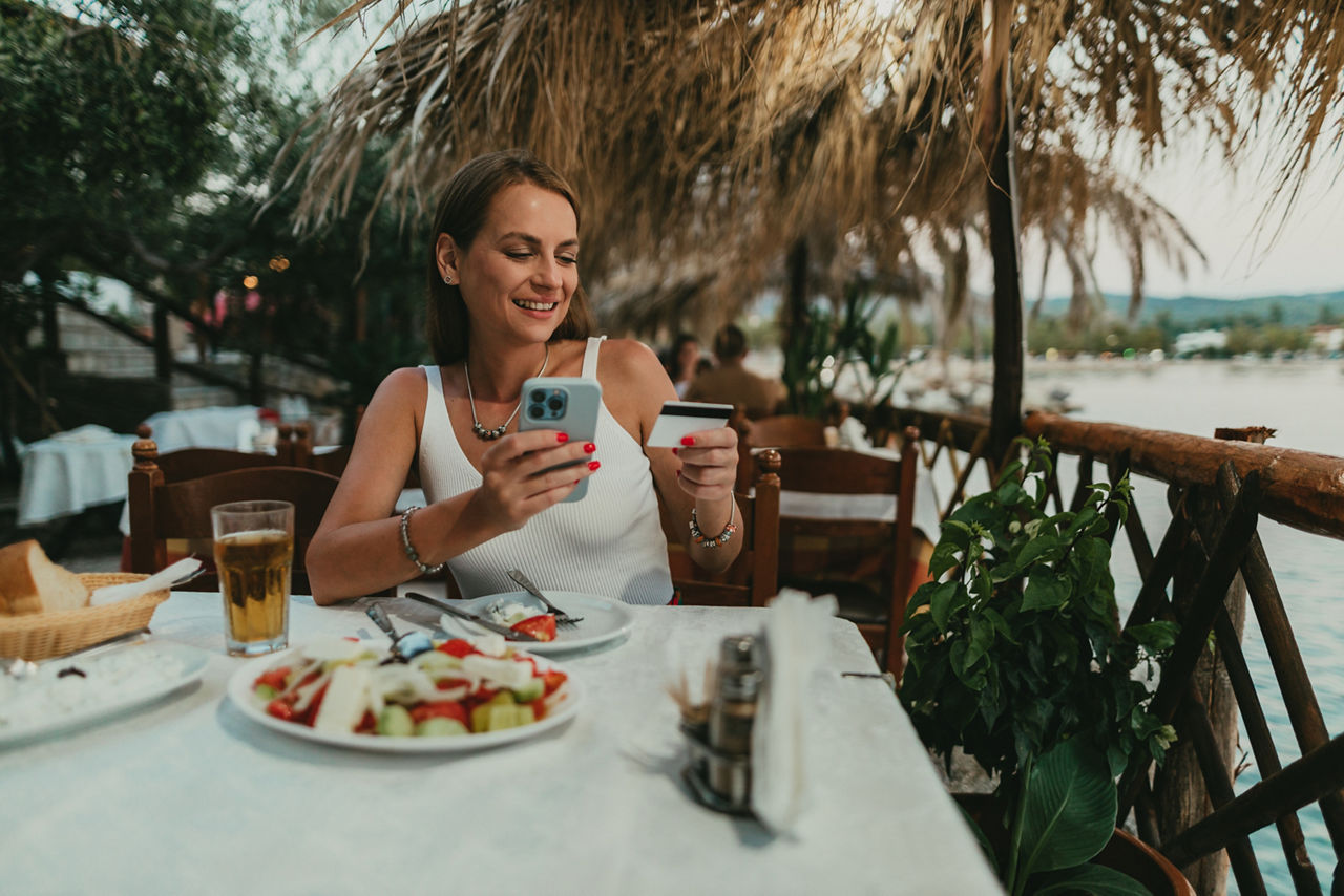Glückliche Frau mit Kreditkarte in der Hand sitzin einem Restaurant