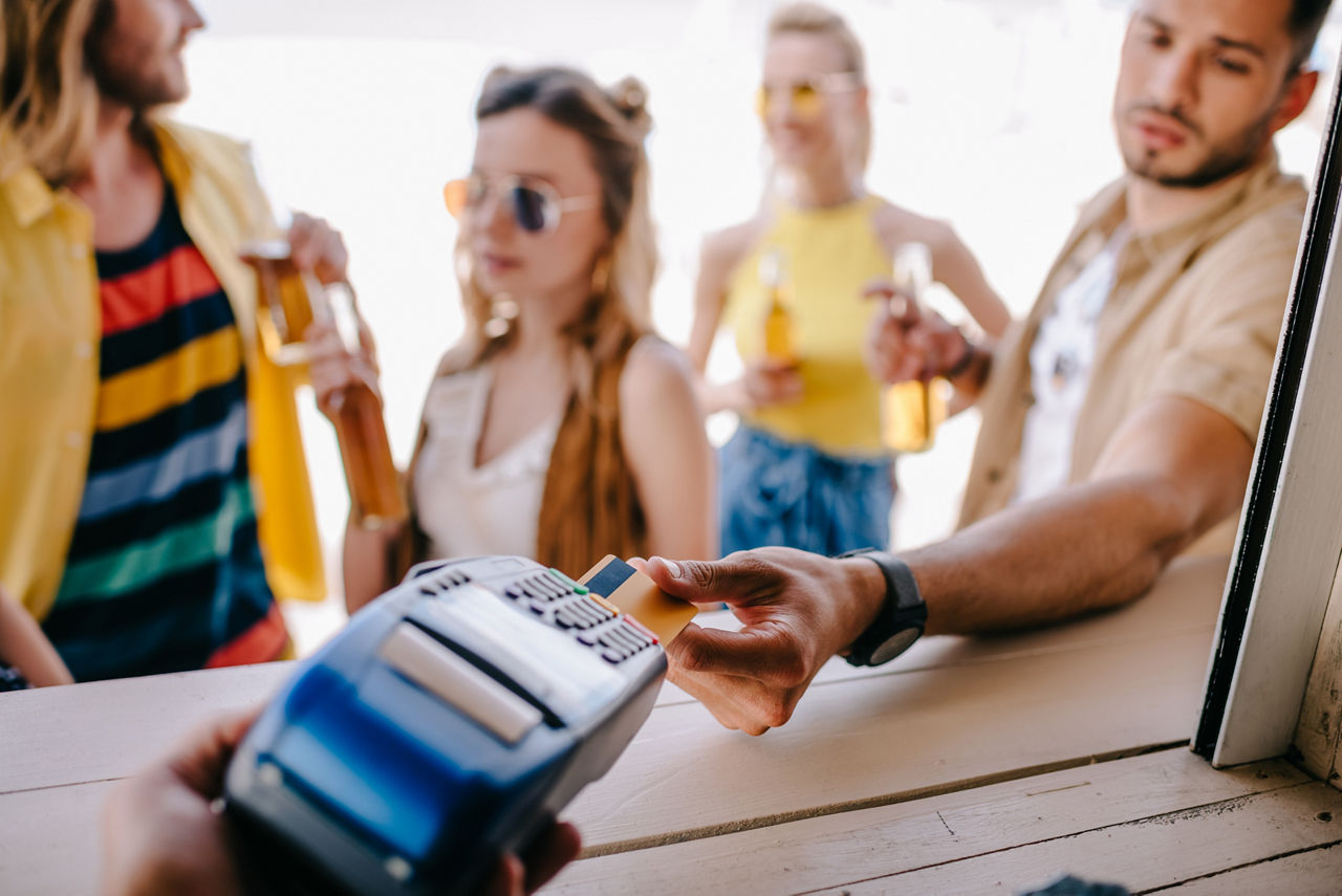 Ein junger Mann bezahlt mit einer Kreditkarte an der Strandbar.