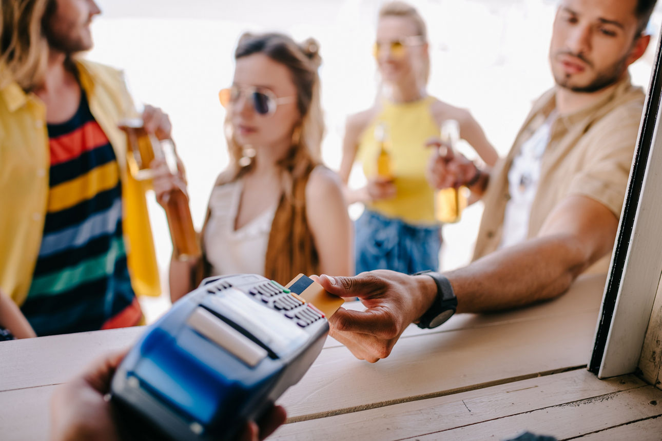 Ein junger Mann bezahlt mit einer Kreditkarte an der Strandbar.