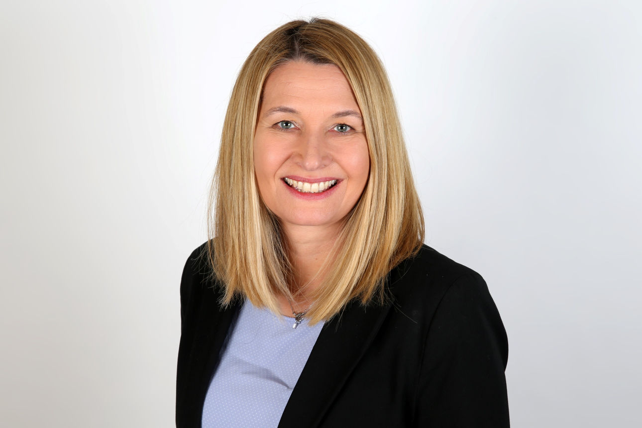 Eine lächelnde Frau schaut in die Kamera.