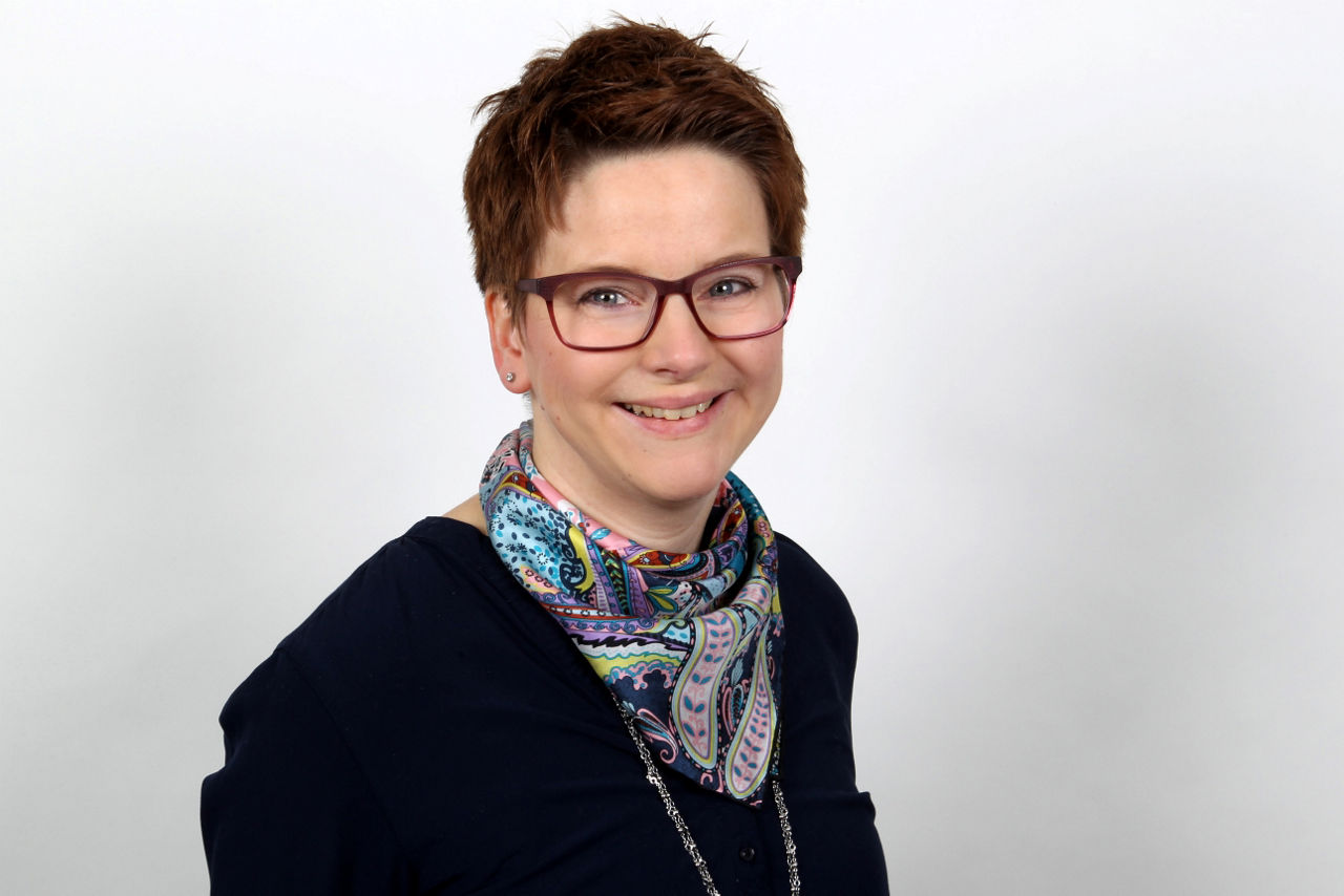 Eine lächelnder Frau schaut in die Kamera.