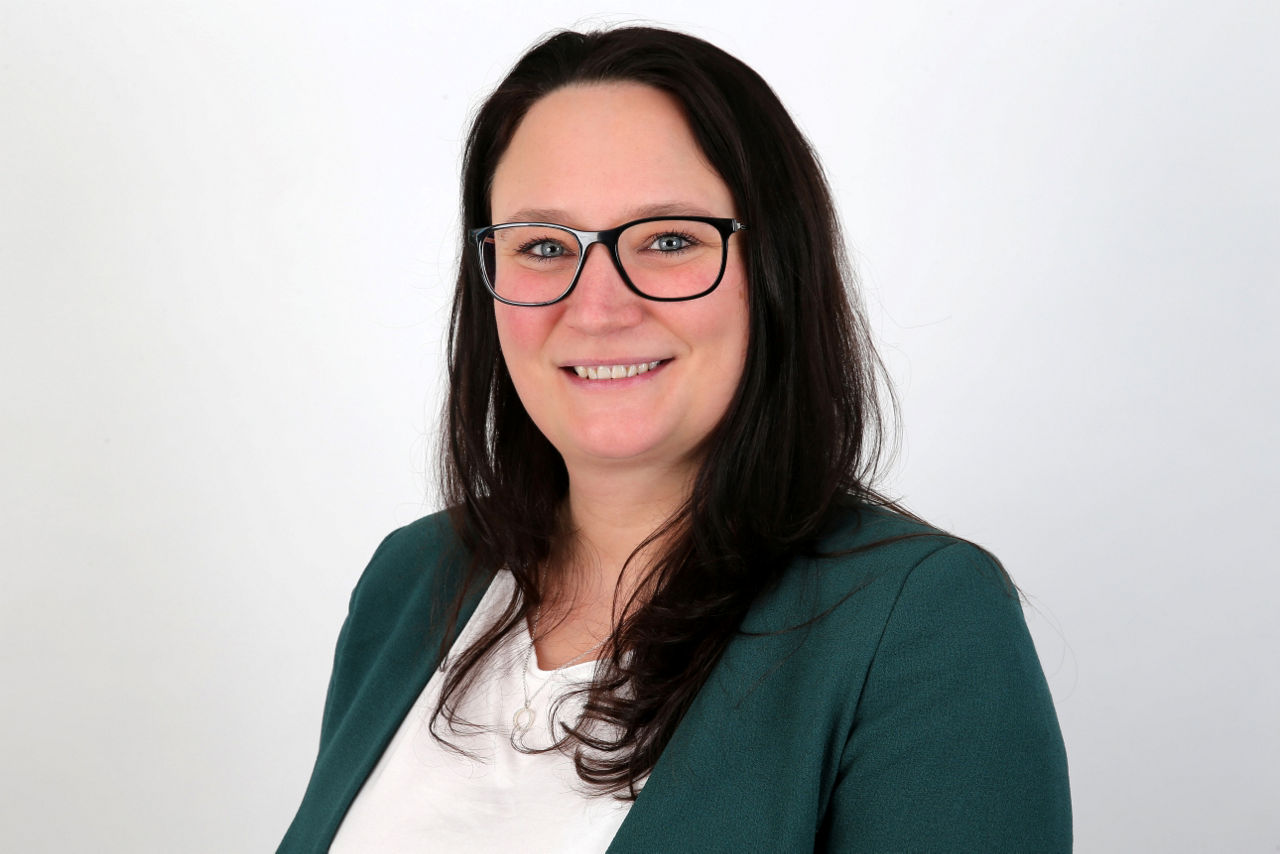 Eine lächelnder Frau schaut in die Kamera.