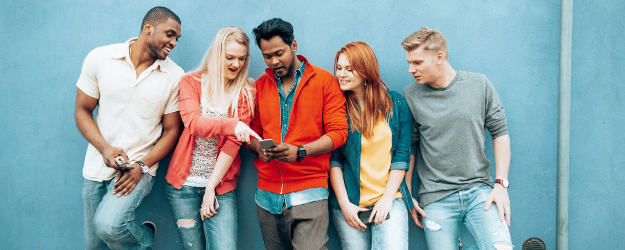 5 junge Menschen schauen gemeinsam auf ein Smartphone