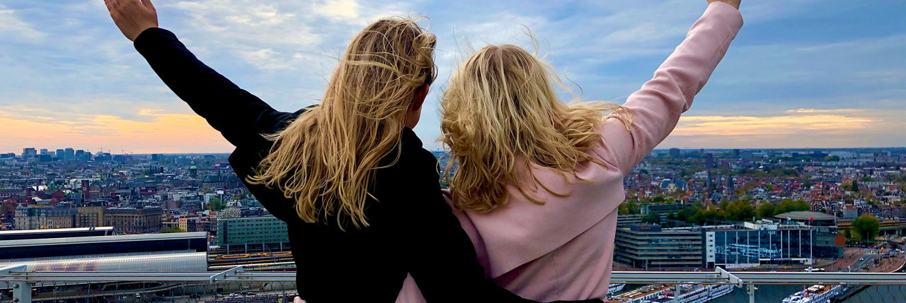 Zwei blonde Mädchen betrachten die Panoramaansicht vom Dach eines Gebäudes