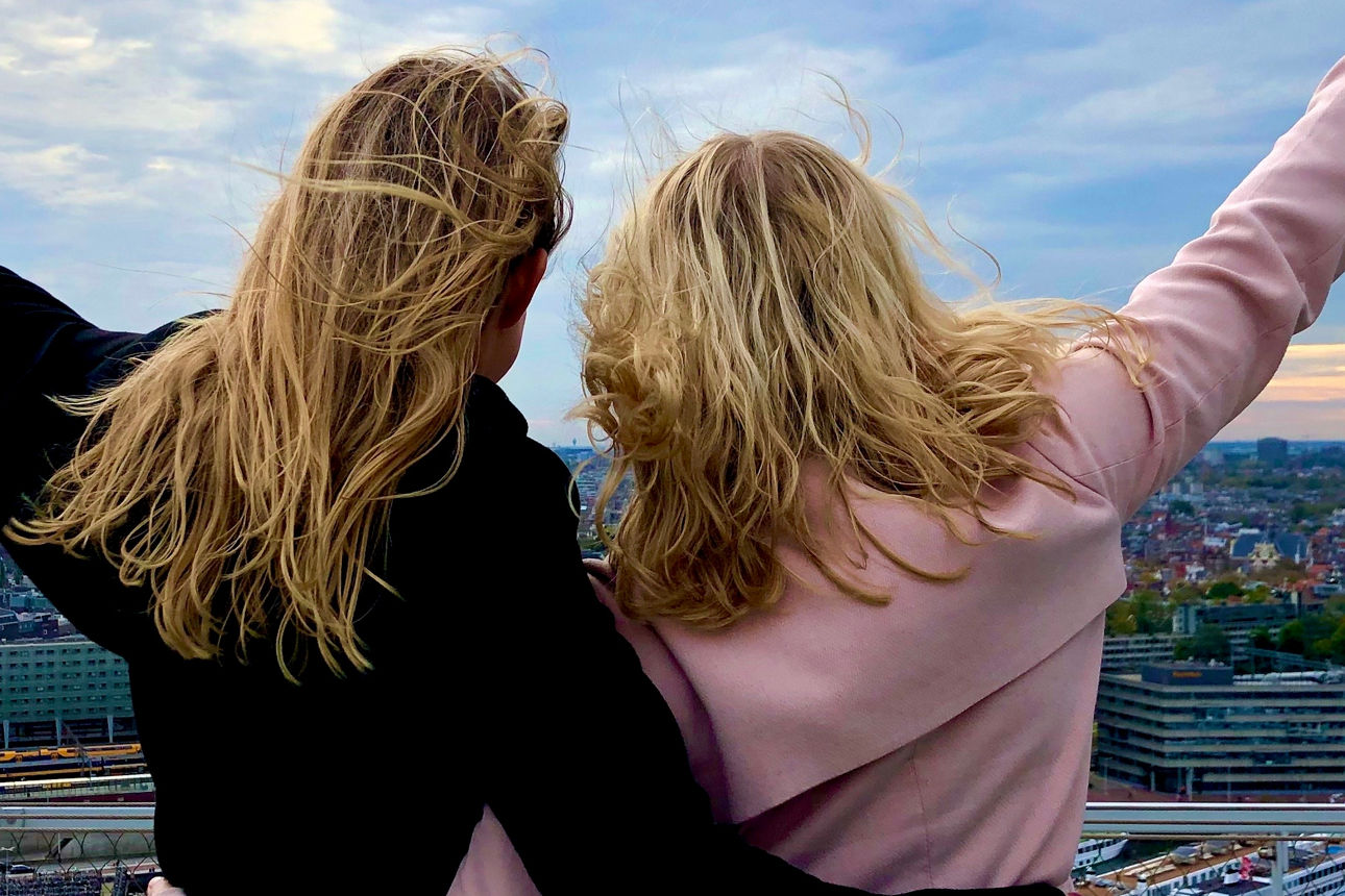 Zwei blonde Mädchen betrachten die Panoramaansicht vom Dach eines Gebäudes