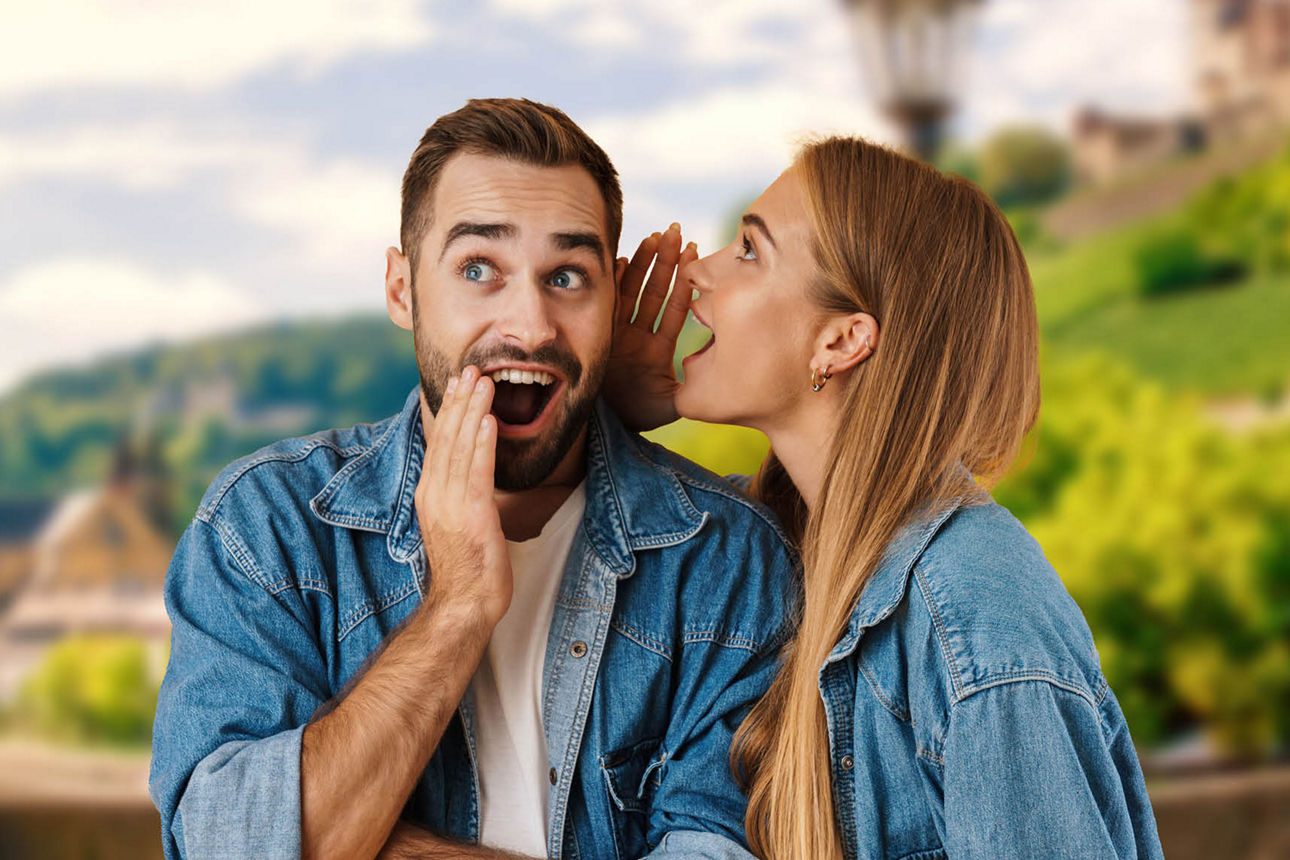 Eine Frau flüstert einem Mann etwas ins Ohr, sie stehen auf dder alten Mainbrücke in Würzburg