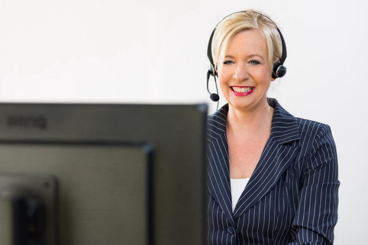 Bankmitarbeiterin mit Headset arbeitet am PC