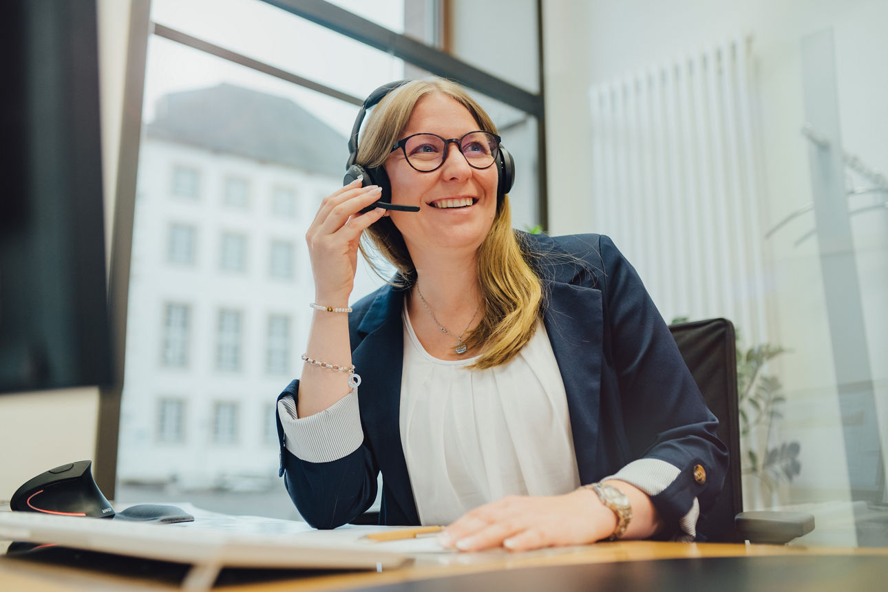 Eine Frau telefoniert im Büro mit ihrem Headset