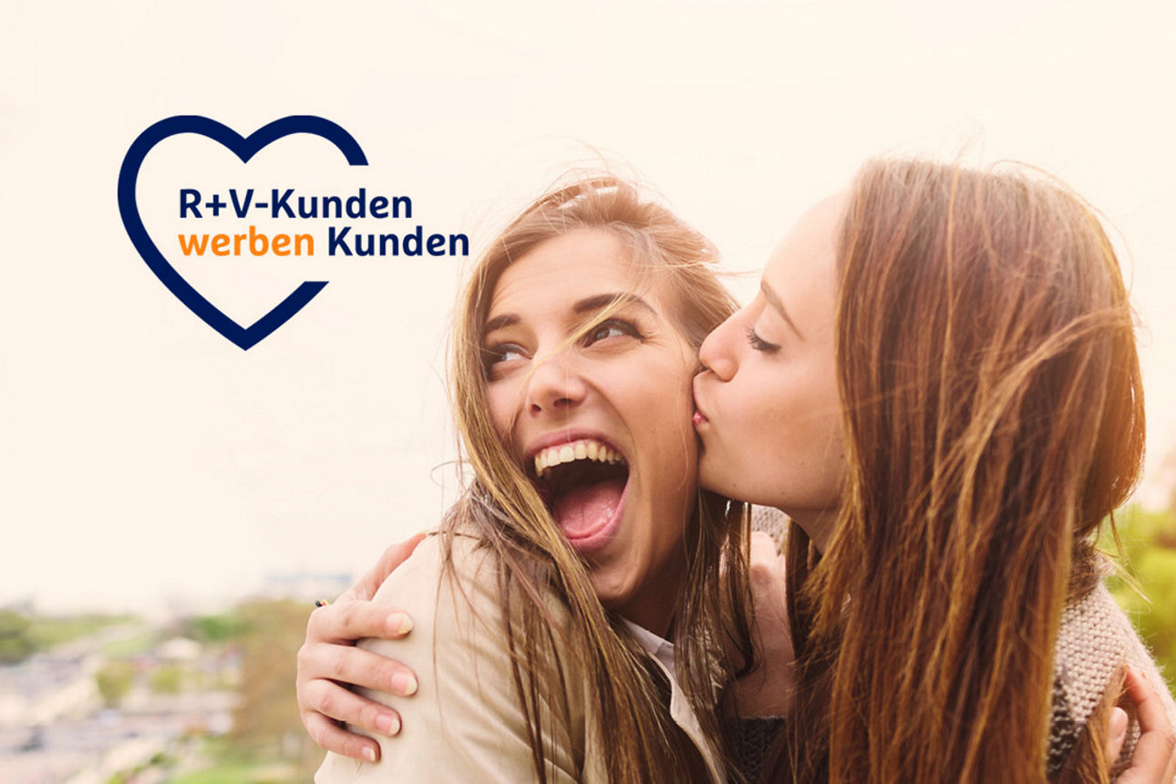 Eine Frau küsst eine andere lächelnde Frau auf die Wange