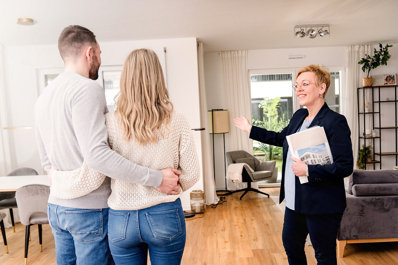 Kundenberaterin zeigt jungem Paar eine Wohnung