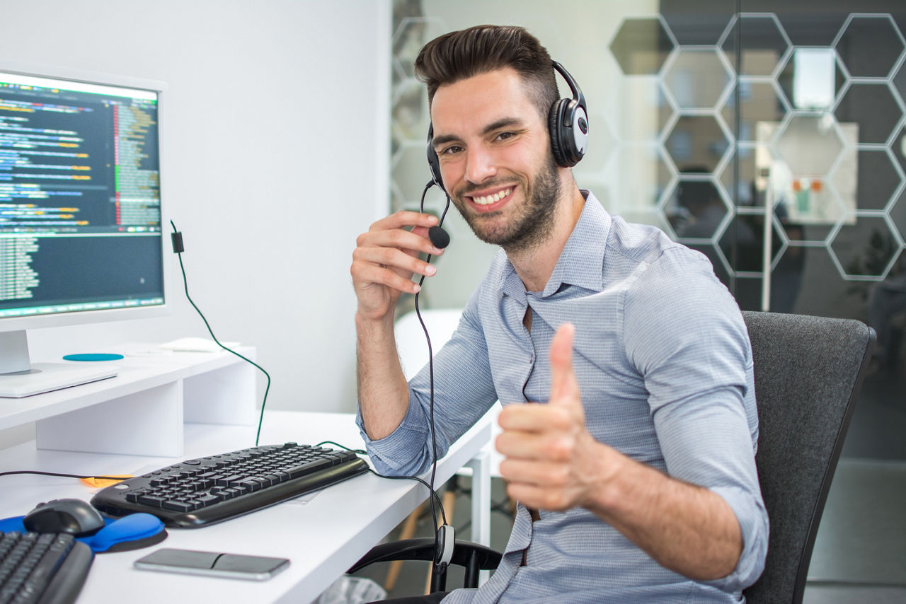Mann am PC beim telefonieren via Headset.
