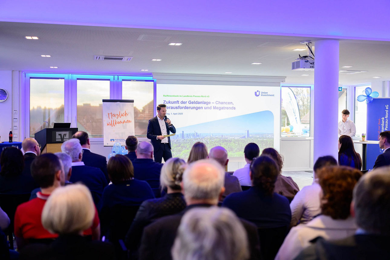 Publikum hört Sprecher auf Bühne zu