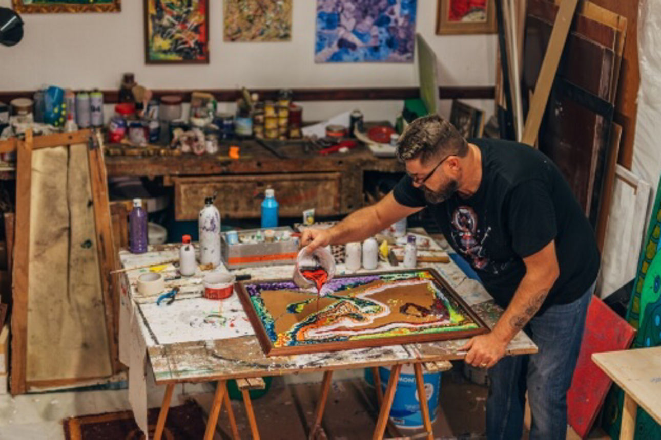 Künstler malt ein Bild in seinem Atelier voller Farben 