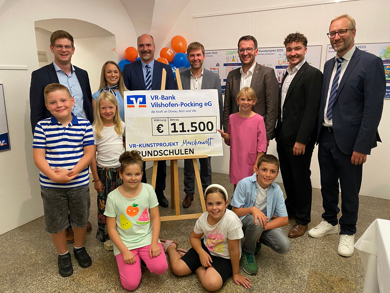 Vorstand und Mitarbeiter der Bank mit den Kindern und einem Spendenscheck