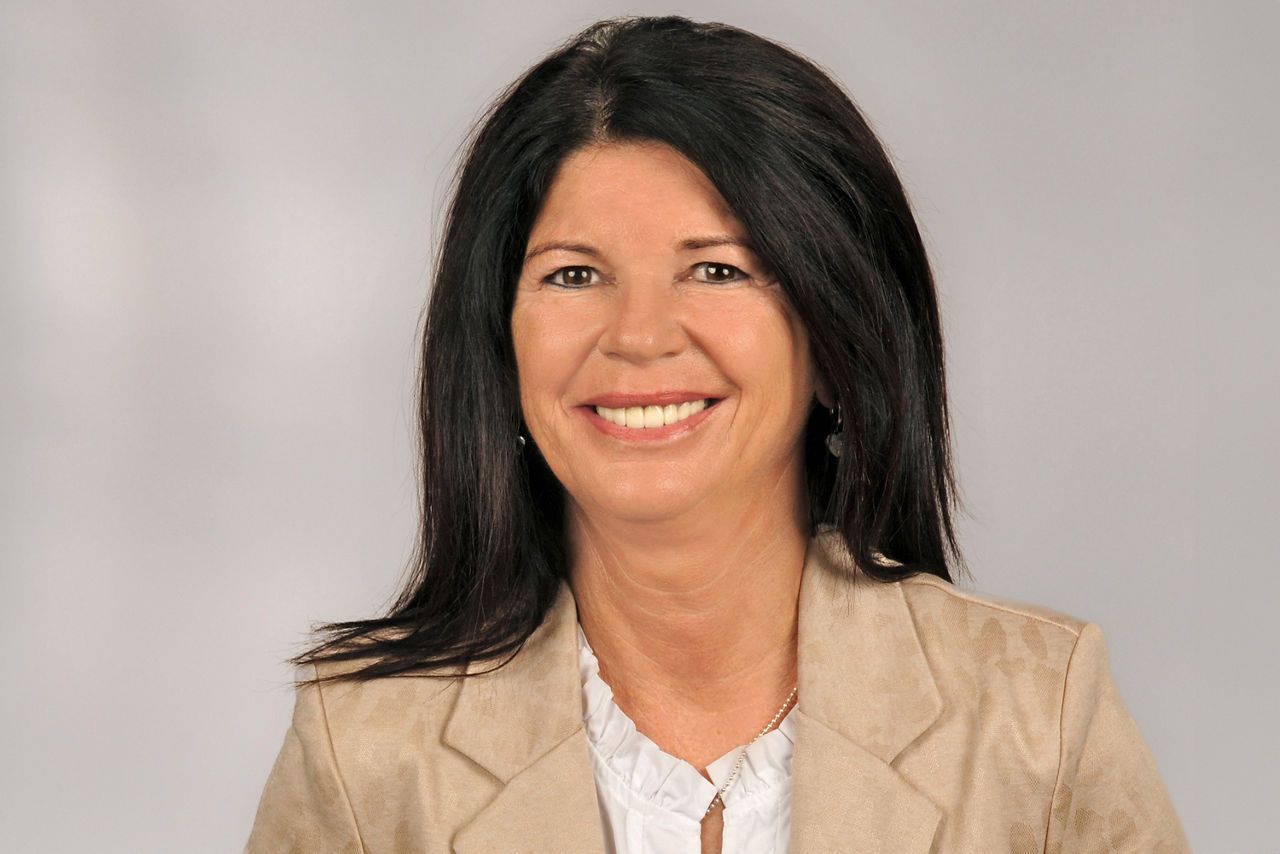 Melanie Kuntze hat schwarze lange Haare, sie trägt eine weiße Bluse und einen beigen Blazer