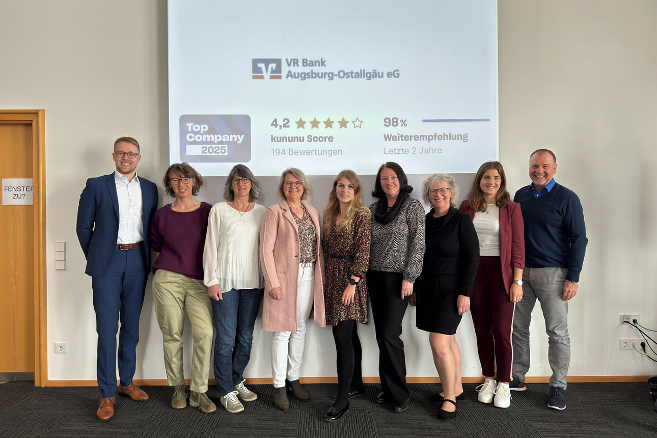 Gruppe von Menschen. Im Hintergrund eine Präsentation mit dem kununu Award 