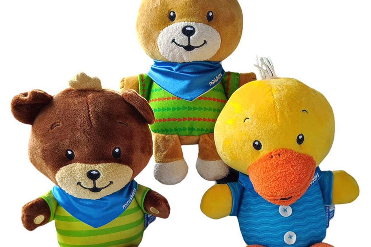 Drei Plüschtiere, ein Teddybär, ein Hase und ein Entchen, gekleidet in Kleidung