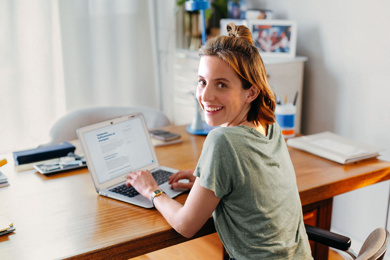 Lächelnde Frau sitzt am Computer.