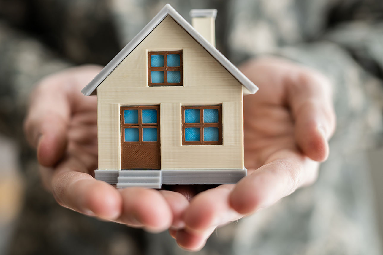 Ein Mann hält ein kleines Haus in seinen Händen