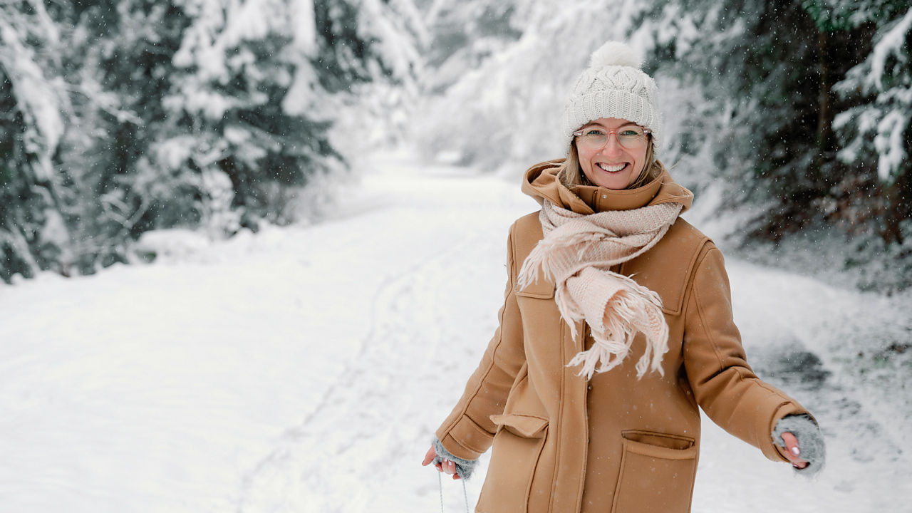 Eine Frau geht im verschneiten Wald Spazieren