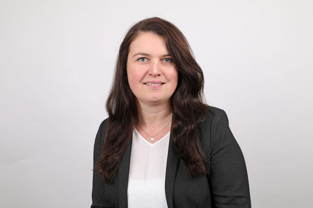 Mitarbeiterin, Janina Langohr, vor weißer wand und lächelt in die Kamera